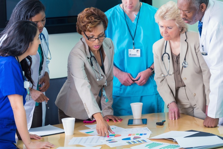 group of health care professionals gathered around a table looking at graphs