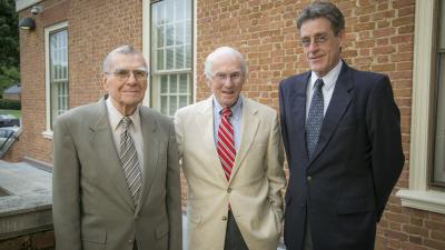 three men standing outside of a building