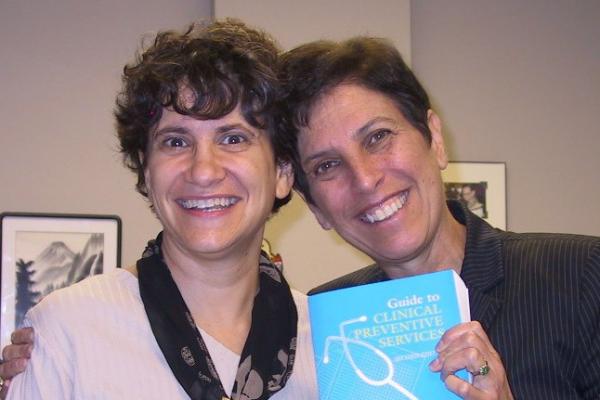 two women, one holding a book