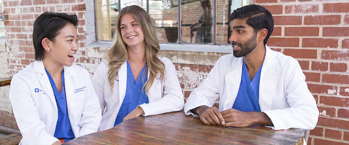 three residents talking at table outside coffee shop