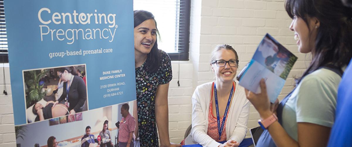 two residents talk to a pregnant woman at a health fair