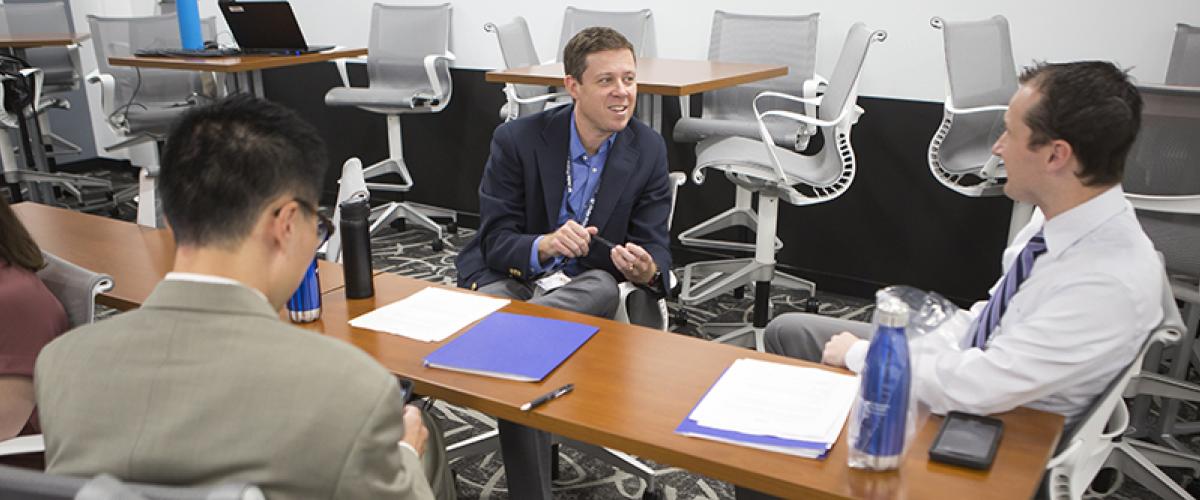 three men talking around a table