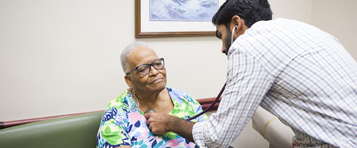 resident listening to the heart of an elderly patient
